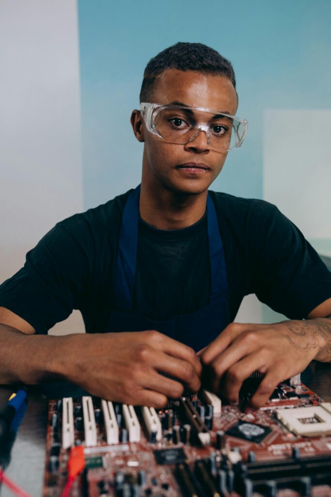 Top view of a focused young technician assembling a motherboard on a desk indoors.